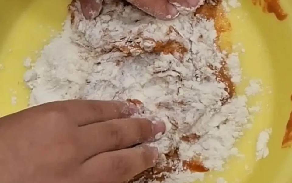 Mani dei bambini manipolano farina in un recipiente giallo