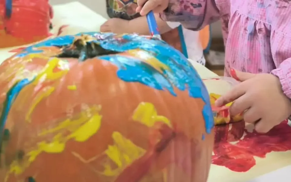 Bambini decorano una zucca con pennelli e colori all’Asilo Busti